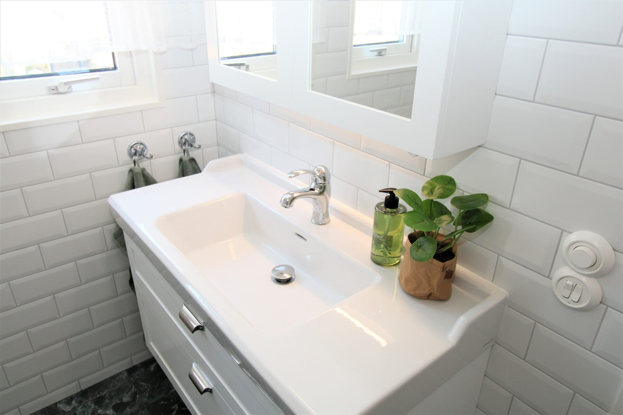 Ljust badrum med takdusch, infälld belysning och stilrena materialval i vitt