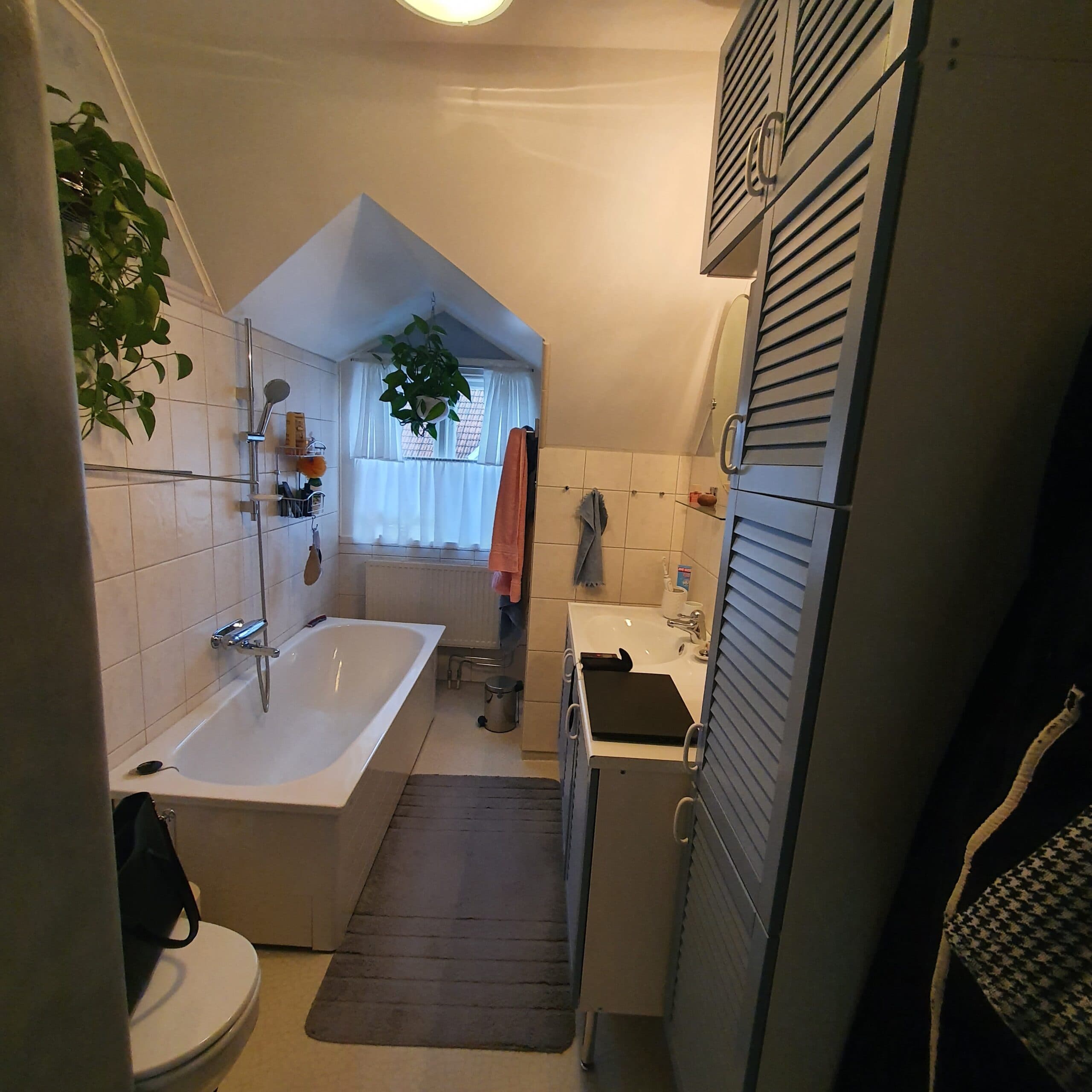 Modernt badrum med stilren design, vitt kakel, grå klinkergolv och badkar