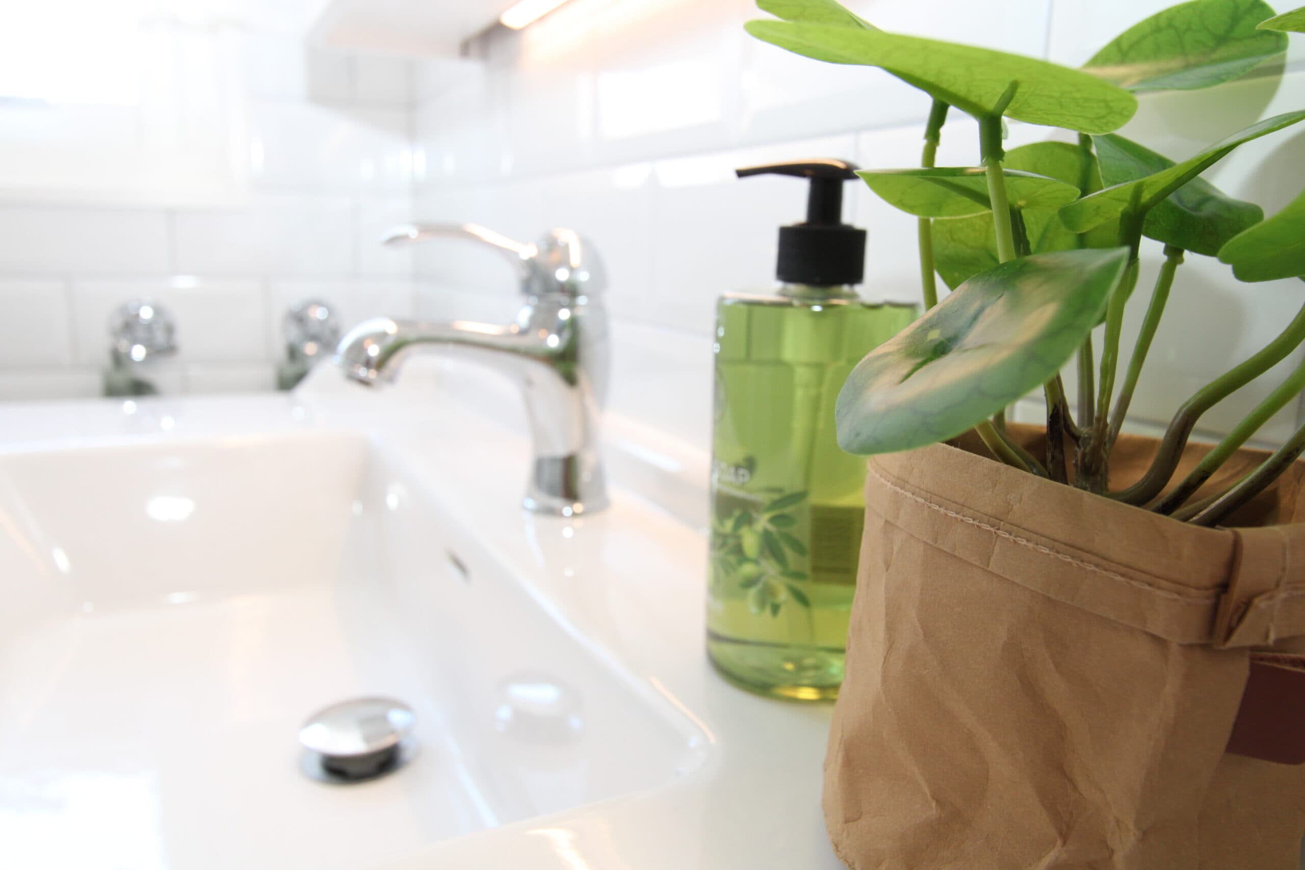 Modernt renoverat badrum med stor spegel, handfat och dekorativ väggbelysning.